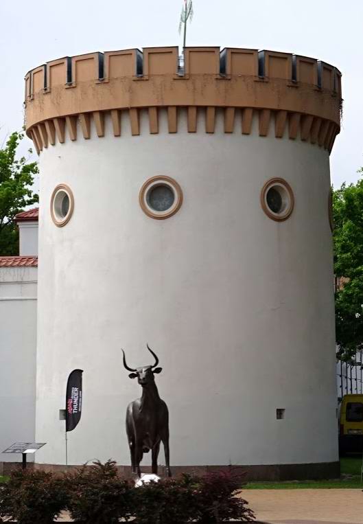 Памятник корове на фоне башни Таурагского замка.